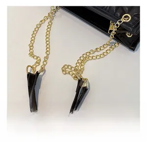 Detail of comfortable shoulder strap with golden metal chain on black pleated leather bag