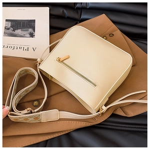 Detail view of cream crossbody bag featuring ethnic jacquard wide strap and smooth finish