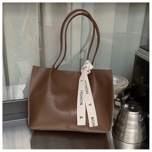 Detail of a dark brown vintage tote bag with decorative fashion ribbon and dual handles