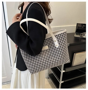 Close-up of houndstooth tote bag worn on shoulder featuring white leather straps