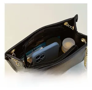 Internal view of black shoulder bag showing main compartment and zipped pocket capacity