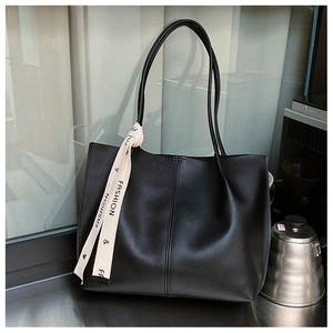 Detailed view of black matte leather tote bag with vertical stitching and fashion ribbon