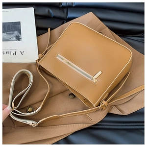 Close-up of tan leather crossbody bag with zipper pocket on a brown suit background