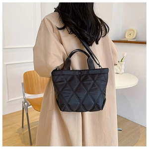 Sac fourre-tout noir matelassé porté en bandoulière montrant le drapé et la sangle