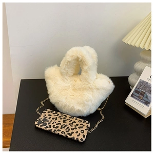 Gros plan d'un sac seau en fausse fourrure blanc cassé avec bandoulière chaîne dorée
