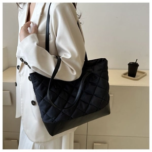 Vista dettagliata di una grande borsa tote nera trapuntata portata a spalla da una modella