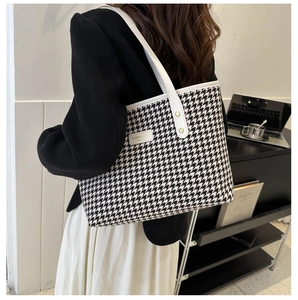 Macro detail of houndstooth fabric texture and white leather stitching on large tote bag