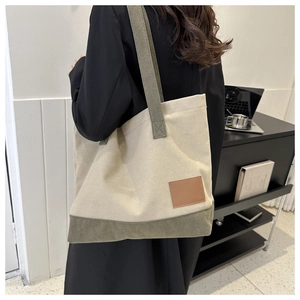 Vista posteriore di una modella con borsa tote in tela bicolore bianco crema e oliva