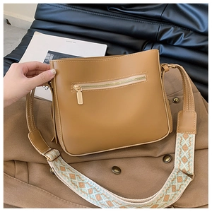 Close-up of brown faux leather crossbody bag with bohemian patterned wide strap