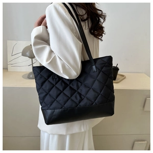 Primo piano della borsa tote nera trapuntata di grande capacità indossata da una modella
