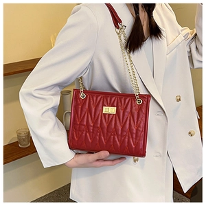 Detail of red quilted leather shoulder bag with gold chain and metal twist lock