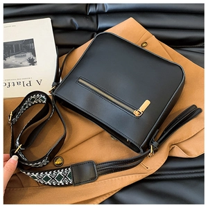 Detail of black leather square bag featuring a gold zipper and ethnic geometric wide strap