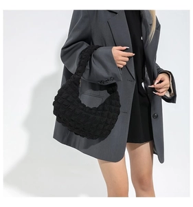 Close-up of black ruched cloud bag texture with 3D bubble fabric and sleek crescent shape