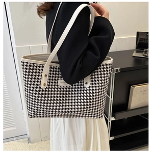 Detail of large houndstooth tote bag with white leather straps and fashion label