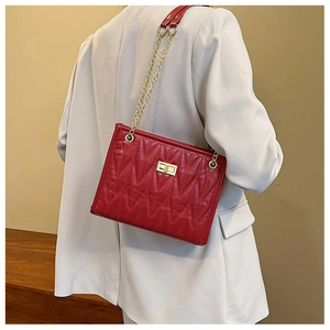 Detailed view of red quilted bag with V-shaped stitching and golden metal chain strap