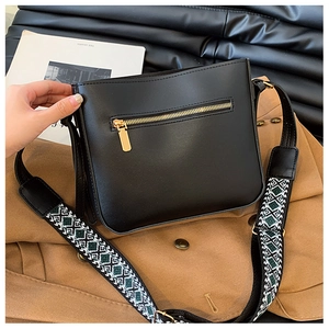 Detail of black PU leather crossbody bag featuring a woven geometric shoulder strap