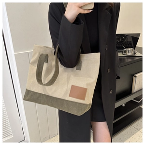 Dettaglio della borsa tote in tela beige e verde oliva indossata da una modella elegante