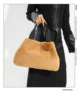 Detail of soft faux fur handbag in camel brown with black handle and decorative pom-pom