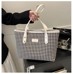 Detail of classic black and white houndstooth tote bag with premium white leather handles