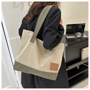Dettaglio della borsa tote in tela color-block con finiture verdi e toppa in pelle marrone