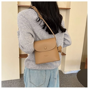 Khaki crossbody square bag with woven shoulder strap and bear charm on model