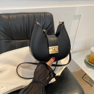 Minimalist black crescent shoulder bag with golden lock and adjustable strap