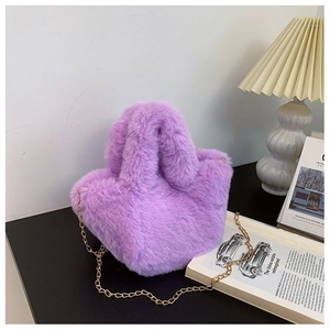Détail du sac seau violet en fausse fourrure avec chaîne dorée sur un bureau élégant