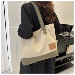 Dettaglio della borsa tote in tela con cuciture a contrasto ed etichetta in pelle marrone