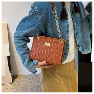 Brown quilted leather shoulder bag with gold chain strap worn by a model in casual style