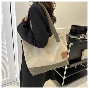Dettaglio della borsa tote in tela con fondo verde oliva e logo in pelle marrone