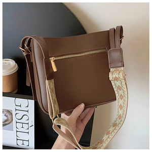 Detail of brown leather bag featuring golden zipper and ethnic jacquard wide strap