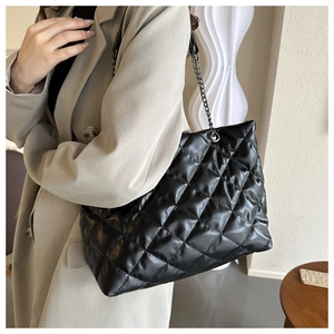 Détail du sac cabas matelassé noir avec bandoulière chaîne porté par un mannequin