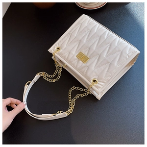 Close-up of white herringbone quilted leather handbag with gold twist lock and chain strap