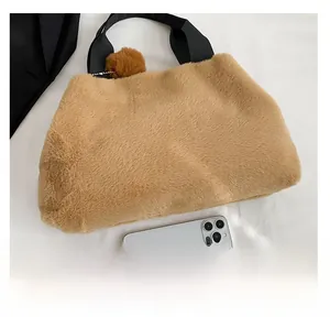 Brown plush shell bag with black strap handles and pompom charm showing large storage capacity