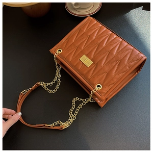 Close-up of vintage brown quilted crossbody bag with gold chain strap and turn-lock detail