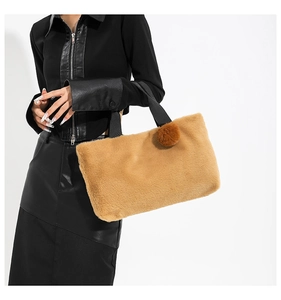 Close-up of soft brown faux fur handbag with black strap and decorative plush ball charm