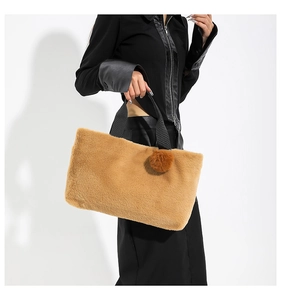 Detail of fluffy brown plush tote bag with furry pom-pom and black woven handle