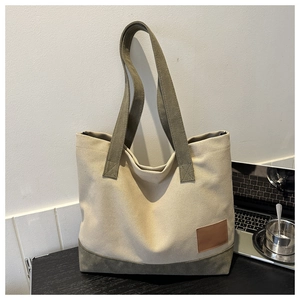 Dettaglio della borsa tote in tela con tracolle verde oliva e toppa in pelle marrone