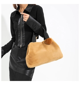 Detail of khaki faux fur bucket bag with black fabric handle and matching pompom charm