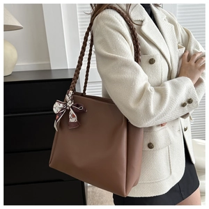 Detail of a brown tote bag with woven shoulder straps and a vintage floral scarf accessory