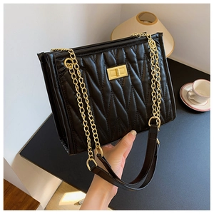 Close-up of black quilted leather shoulder bag featuring gold chain and turn-lock closure
