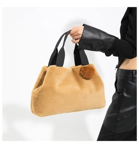 Detailed texture of caramel faux fur bucket bag with plush charm and black handles