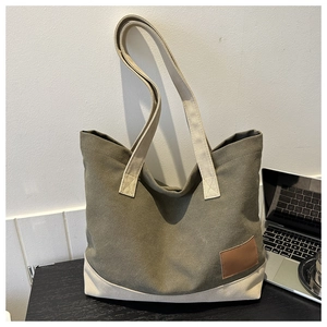 Dettaglio della borsa tote in tela verde militare con manici crema e toppa in pelle