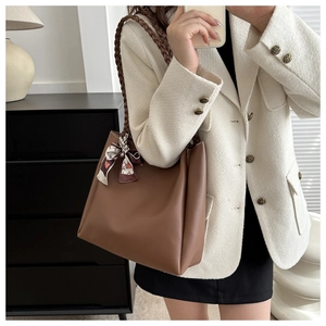 Brown leather tote bag with woven shoulder strap and decorative geometric print silk scarf