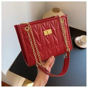 Detailed close-up of red quilted leather shoulder bag with gold chain and twist lock