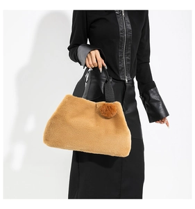 Detail of camel plush bucket bag featuring soft faux fur texture and a fuzzy pom-pom charm