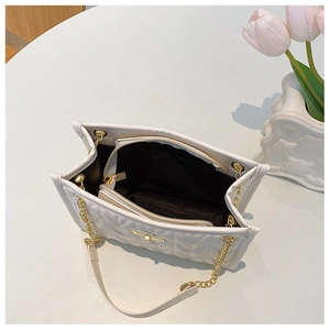 Detail of cream quilted chain shoulder bag interior with compartments and gold hardware