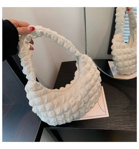 Close-up of white popcorn fabric cloud bag featuring textured bubble pleats and moon shape