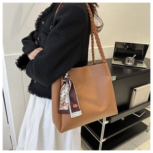 Brown leather tote bag featuring woven straps and elegant printed silk scarf detail