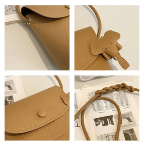 Detail view of tan pebble leather crossbody bag with elephant charm and woven strap